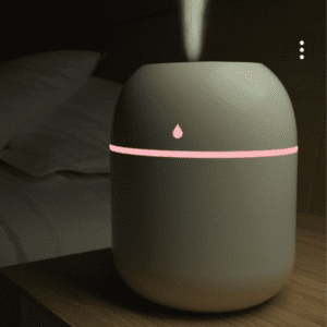 Modern aroma diffuser on wooden nightstand, enhancing relaxation with mist and soft lighting.