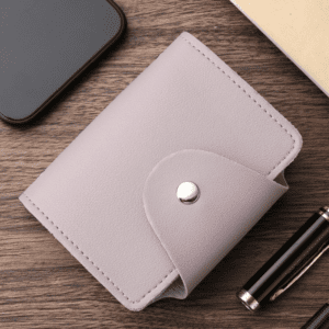 Stylish lavender wallet with accessories, smartphone, notebook, and pen on wooden surface.