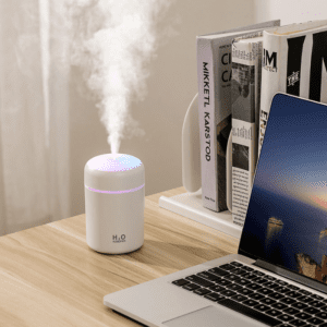 Modern minimalist desk setup with a stylish humidifier, laptop, and organized books for productivity.