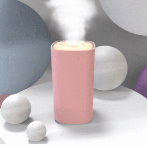 Modern pink diffuser with steam, surrounded by pastel spheres, creating a serene ambiance.