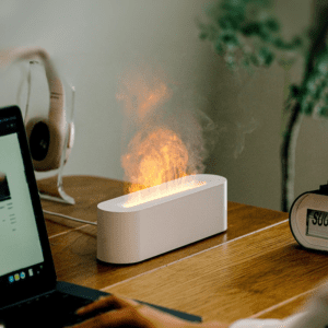 Sleek modern workspace featuring a stylish flame device, laptop, and headphones for productivity.